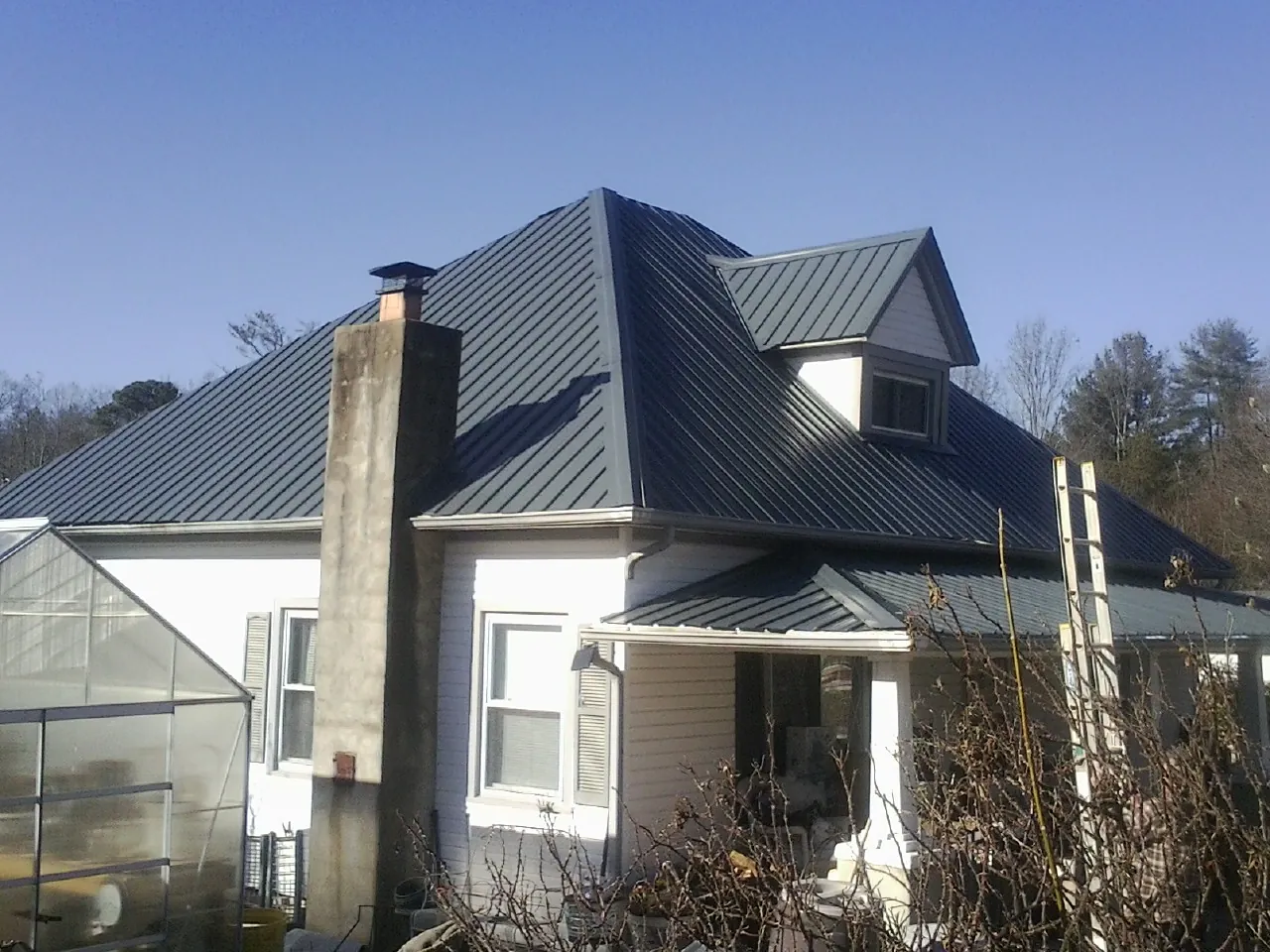 Dark blue standing seam metal roof on a white farmhouse with dormer — Slate & Tile Roof Repair by Roofing Brothers in Quarryville