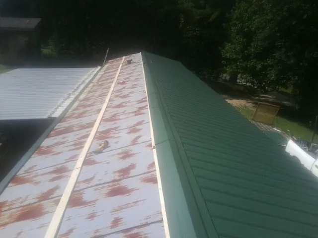 Old rusted panels beside newly installed green metal roofing — Wind Damage Roof Repair by Roofing Brothers in Quarryville