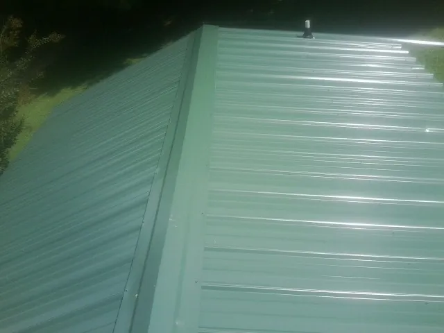 New green metal panels meeting at the ridge of a roof — Flat Roof Repair work by our crew in Quarryville