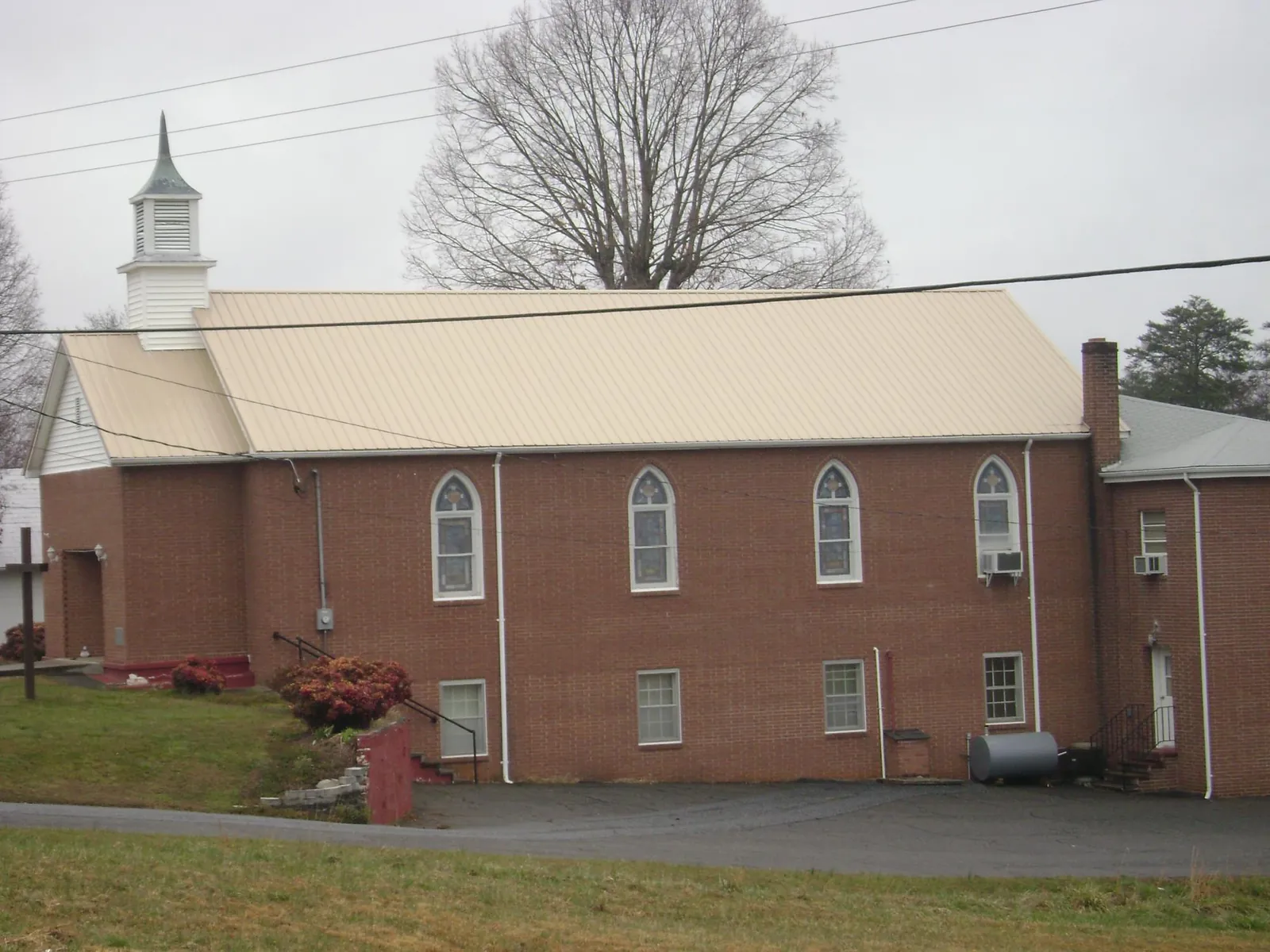 New tan metal roof on a brick church with a white steeple in Quarryville