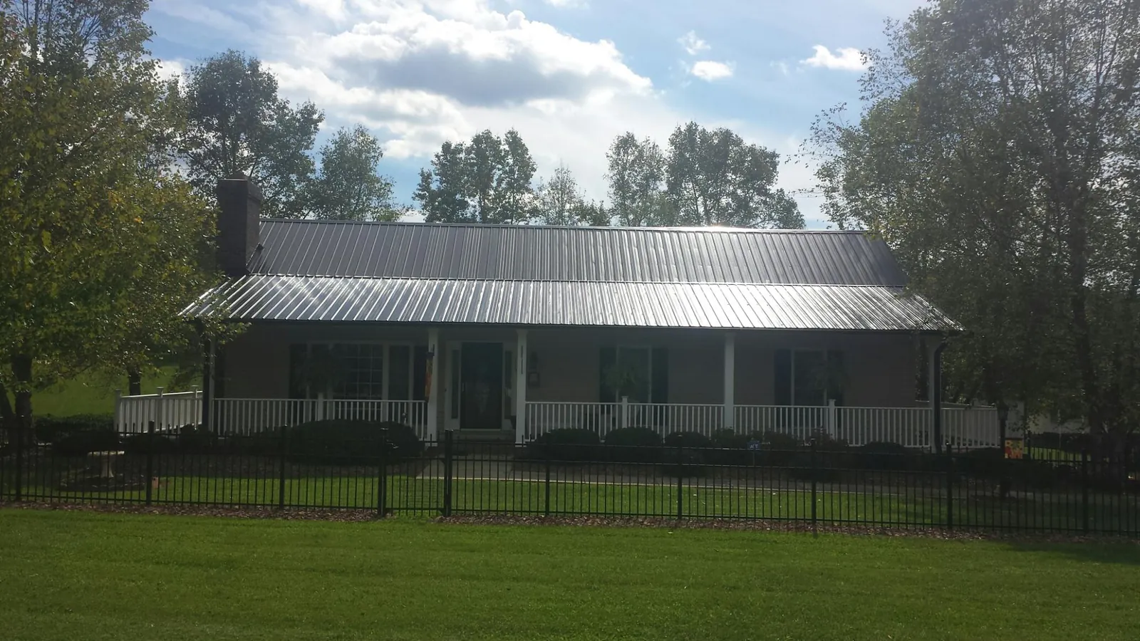 Gray metal roof on a brick ranch with a full width front porch — Gutter Guard Installation work by our crew in Quarryville