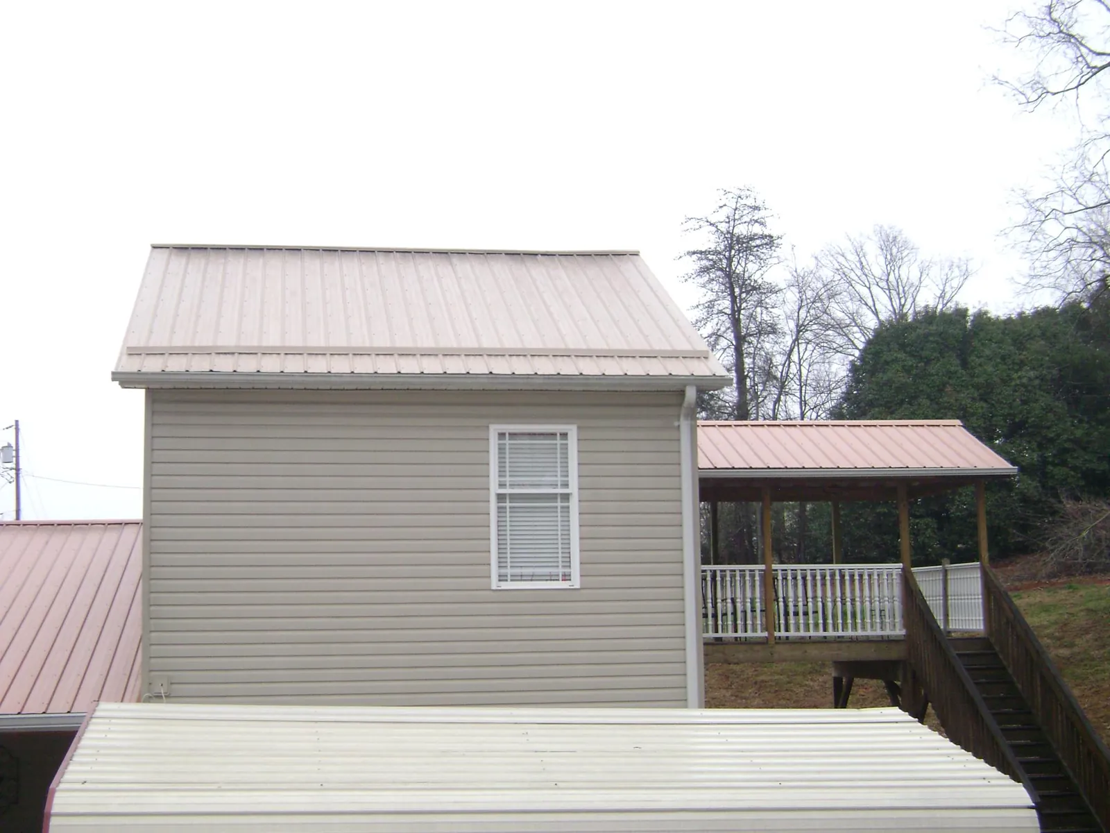 Tan metal roofs on a two story addition and attached porch, from a Roof Replacement job in Quarryville