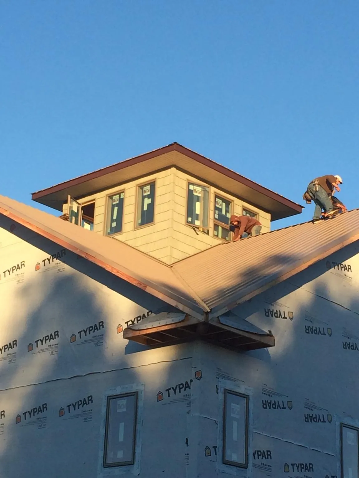 Roofers working around a rooftop cupola on a new metal roof at sunset — Roof Waterproofing in Quarryville by Roofing Brothers